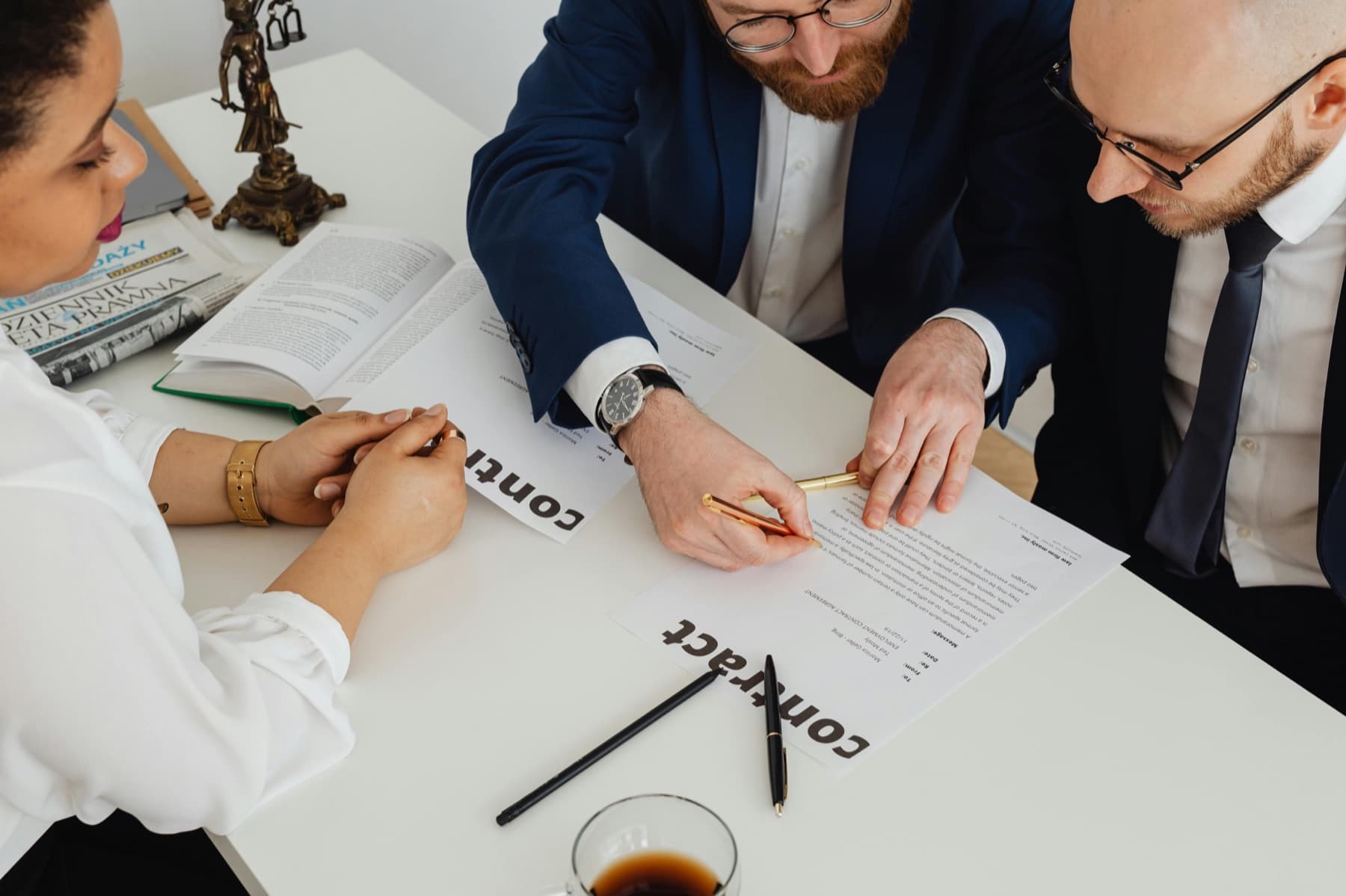 Lawyers reviewing contract paperwork with a client at a desk.