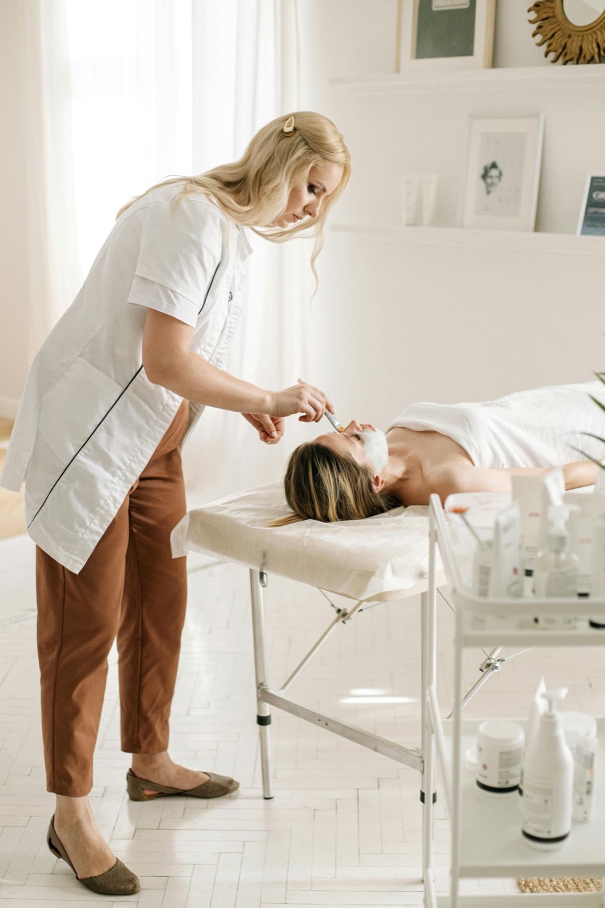 An aesthetician applying a facial treatment in a bright med spa room.